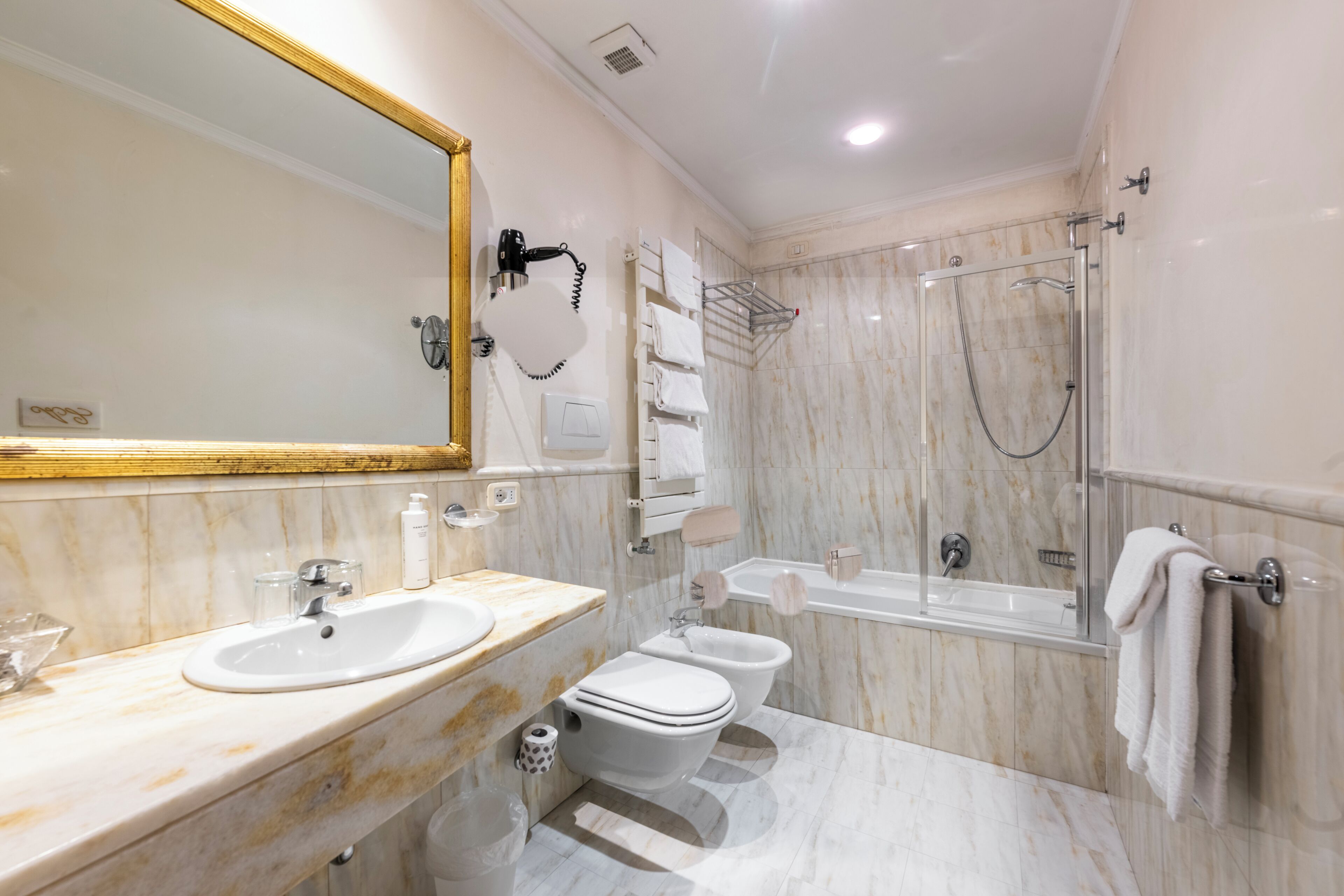 A modern bathroom with a marble sink, a toilet, a bidet, a bathtub, and a shower.
