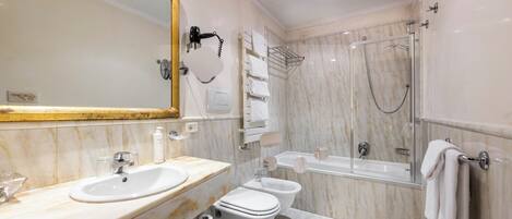 A modern bathroom with a marble sink, a toilet, a bidet, a bathtub, and a shower.