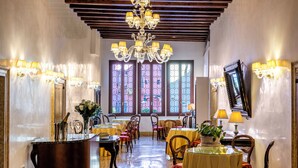 Un hall d’hôtel agrémenté d’un lustre, de plusieurs tables recouvertes de nappes jaunes et de chaises.