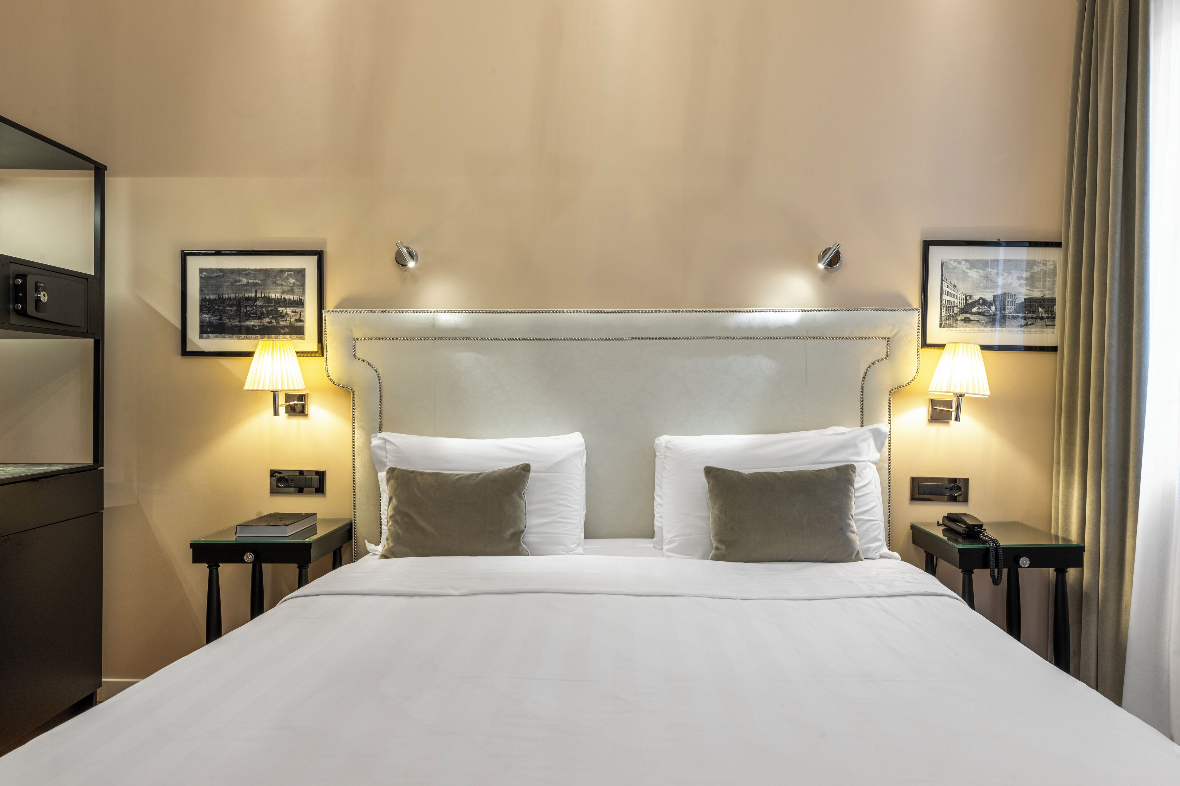 A hotel room with a large bed, two bedside tables with lamps, and framed pictures on the walls.