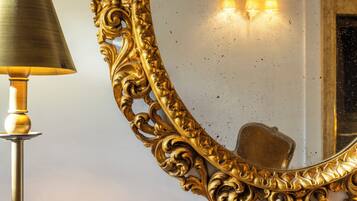Ein goldverzerrter Spiegel mit einer Lampe daneben.