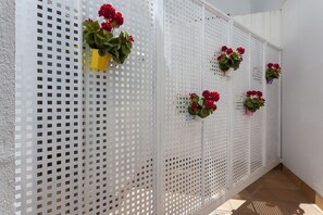 A white perforated partition with potted red flowers. - Hotel AACR Museo (Seville)