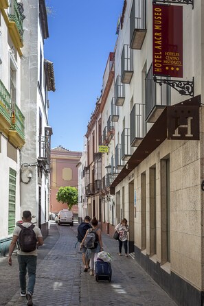 A narrow cobblestone street lined with historic buildings, a sign for Hotel Aacr Museo, and a parked van. - Hotel AACR Museo (Seville)