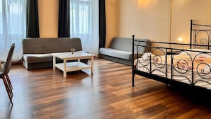 A room with a bed, two sofas, a small table, and a chair. - Residence Casa Italia  (Prague)