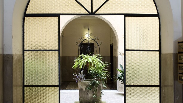An arched doorway with a tiled floor leading to a courtyard with a potted plant. - Best Vatican B&B (Rome)