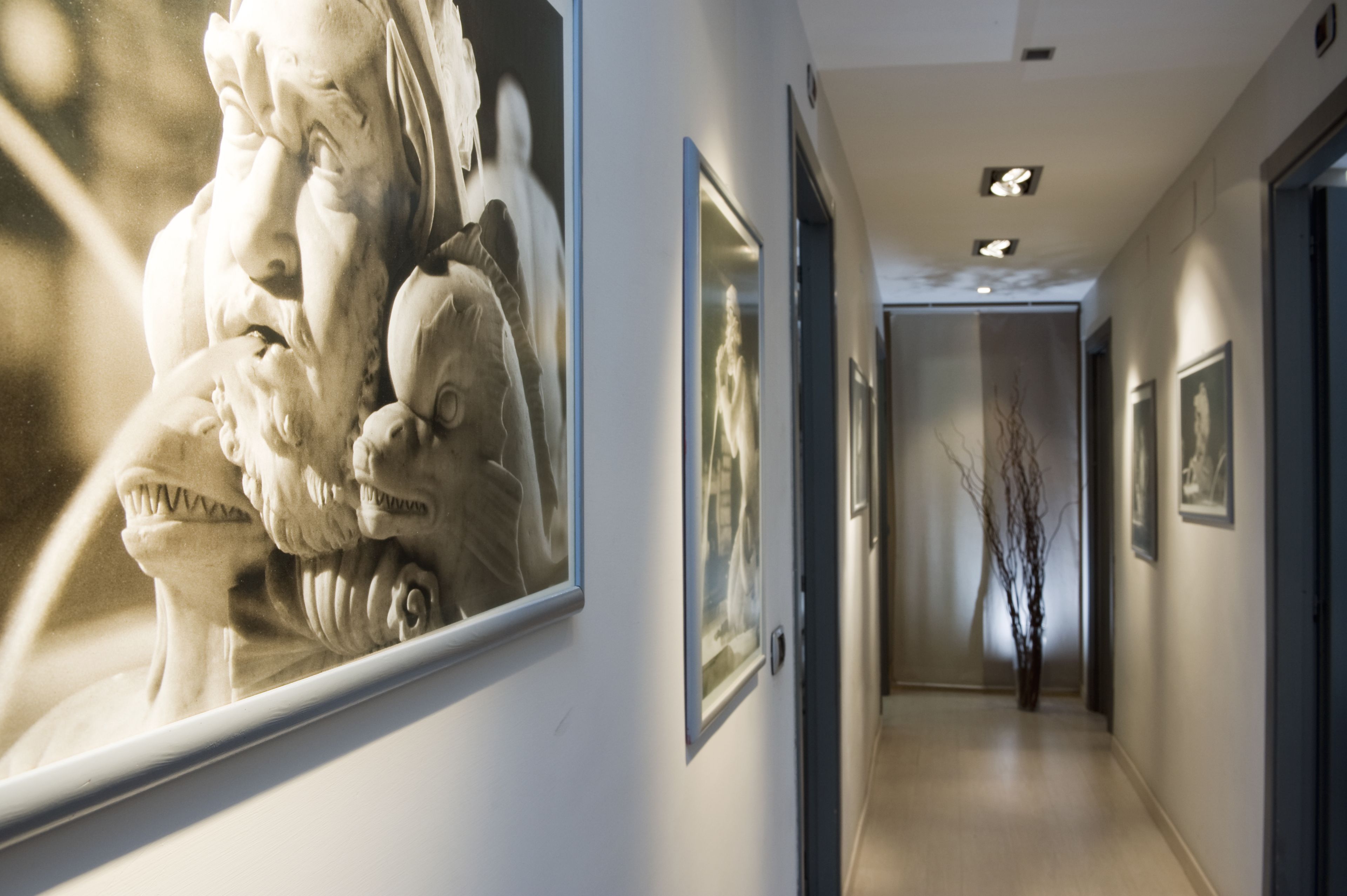 A hallway with framed artworks on the walls, a modern light fixture on the ceiling, and a minimalist decor style.