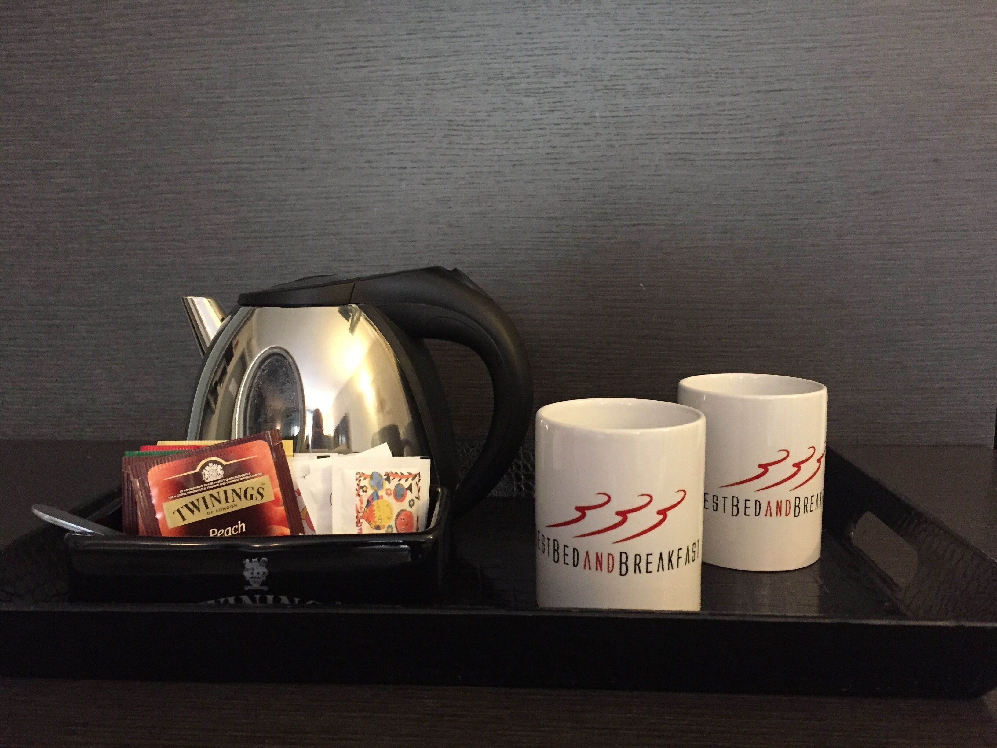 Una bandeja con una tetera, dos tazas y una caja de té Twinings.