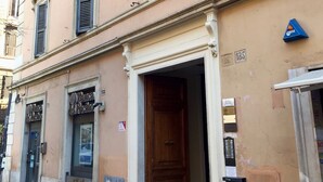 A building with multiple windows, a wooden door, and a sign for a bank. - Best Vatican B&B (Rome)