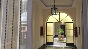 A hallway with a tiled floor, a decorative ceiling light, and a view into a room with a plant. - Best Vatican B&B (Rome)
