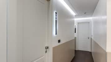 Un pasillo con una puerta identificada como 204, un interruptor de luz y otra puerta al final.