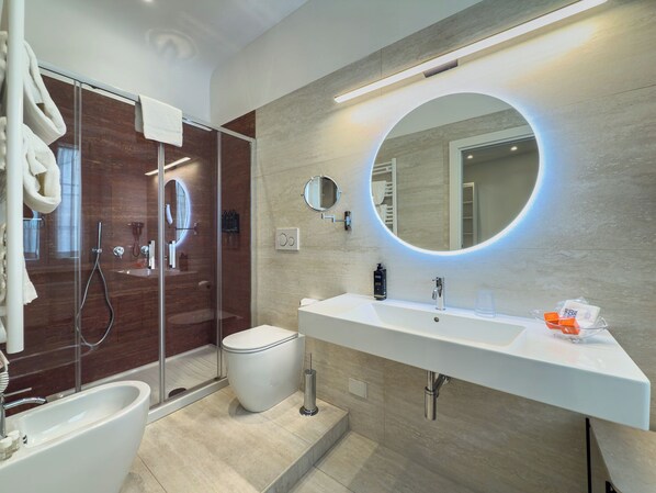 A modern bathroom with a glass-enclosed shower, a white sink with a mirror, and a toilet. - Hotel Abruzzi (Rome)
