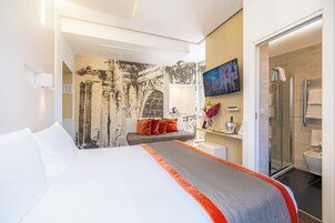 Et hotelværelse med en stor seng, en sofa, brusebad og badeværelse.