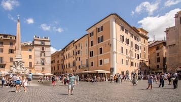 Ein historischer Platz mit Kopfsteinpflaster, einer markanten Fontäne und klassischer Architektur.