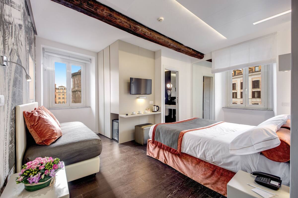 Una habitación de hotel moderna con cama, escritorio, televisor y ventana con vista a la ciudad.