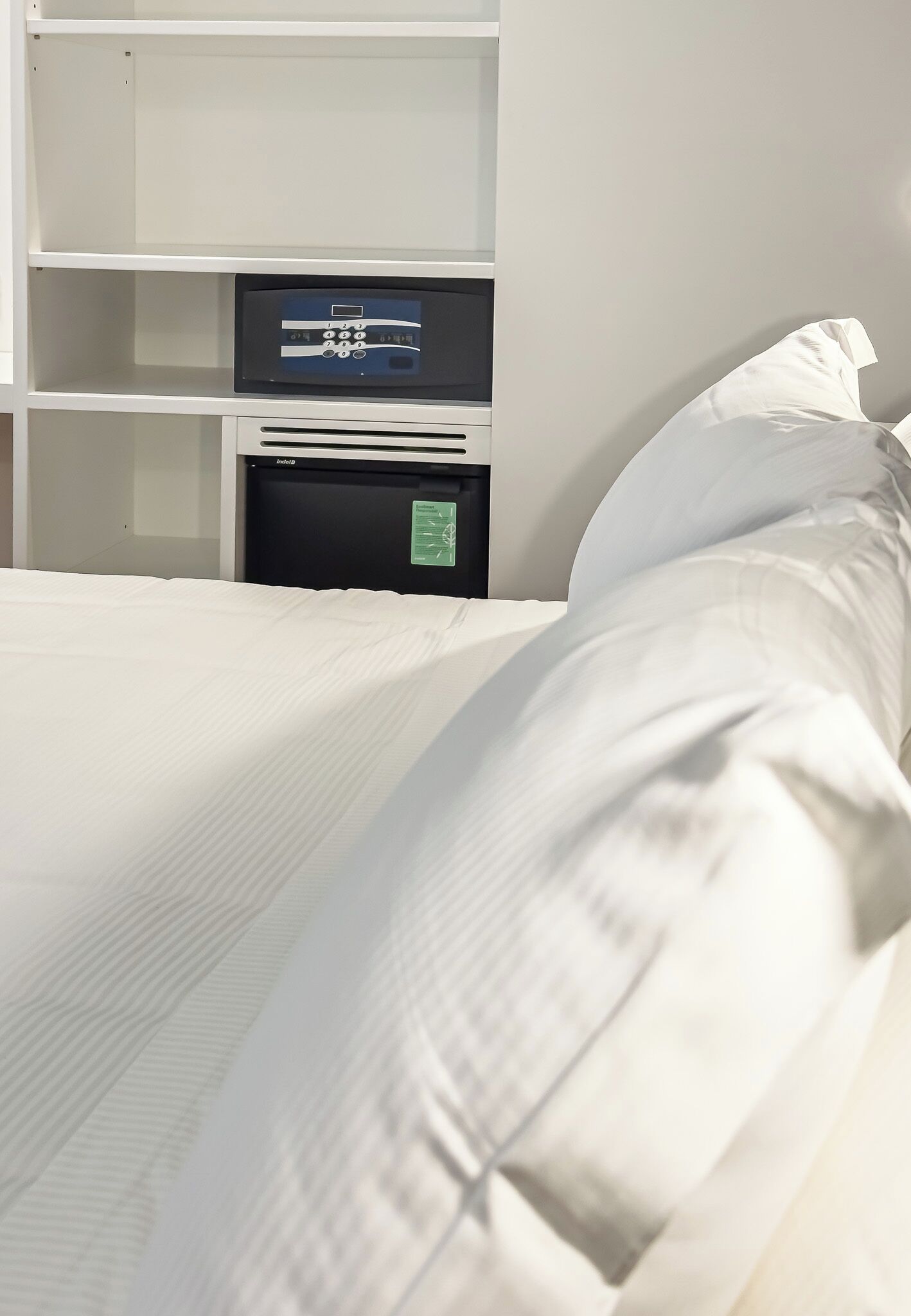 Una habitación de hotel con una cama, un panel de control y una repisa.