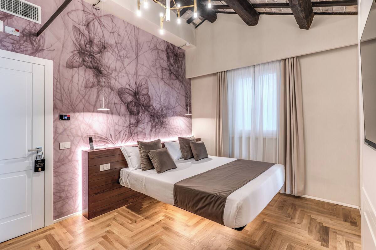 Un dormitorio moderno con cabecera de madera, cama grande, pared con diseño de mármol y suelo de madera.