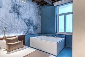 A modern bathroom with a large bathtub, a window with frosted glass, and a marble-patterned wall. - Hotel Abruzzi (Rome)