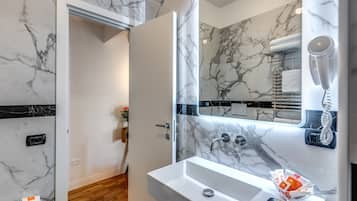 A bathroom with a marble sink, a hairdryer, and a towel rack.