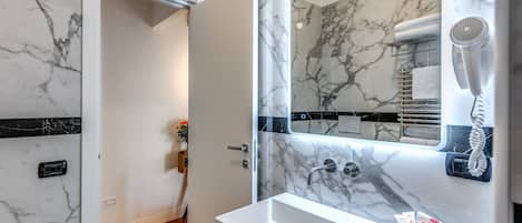 A bathroom with a marble sink, a hairdryer, and a towel rack.