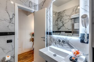 Un baño con lavamanos de mármol, secador de pelo y toallero.