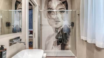 Un baño moderno con cabina de ducha de vidrio, un lavabo blanco y un espejo grande.