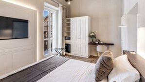 A modern bedroom with a bed, a TV, a desk, and a wardrobe.