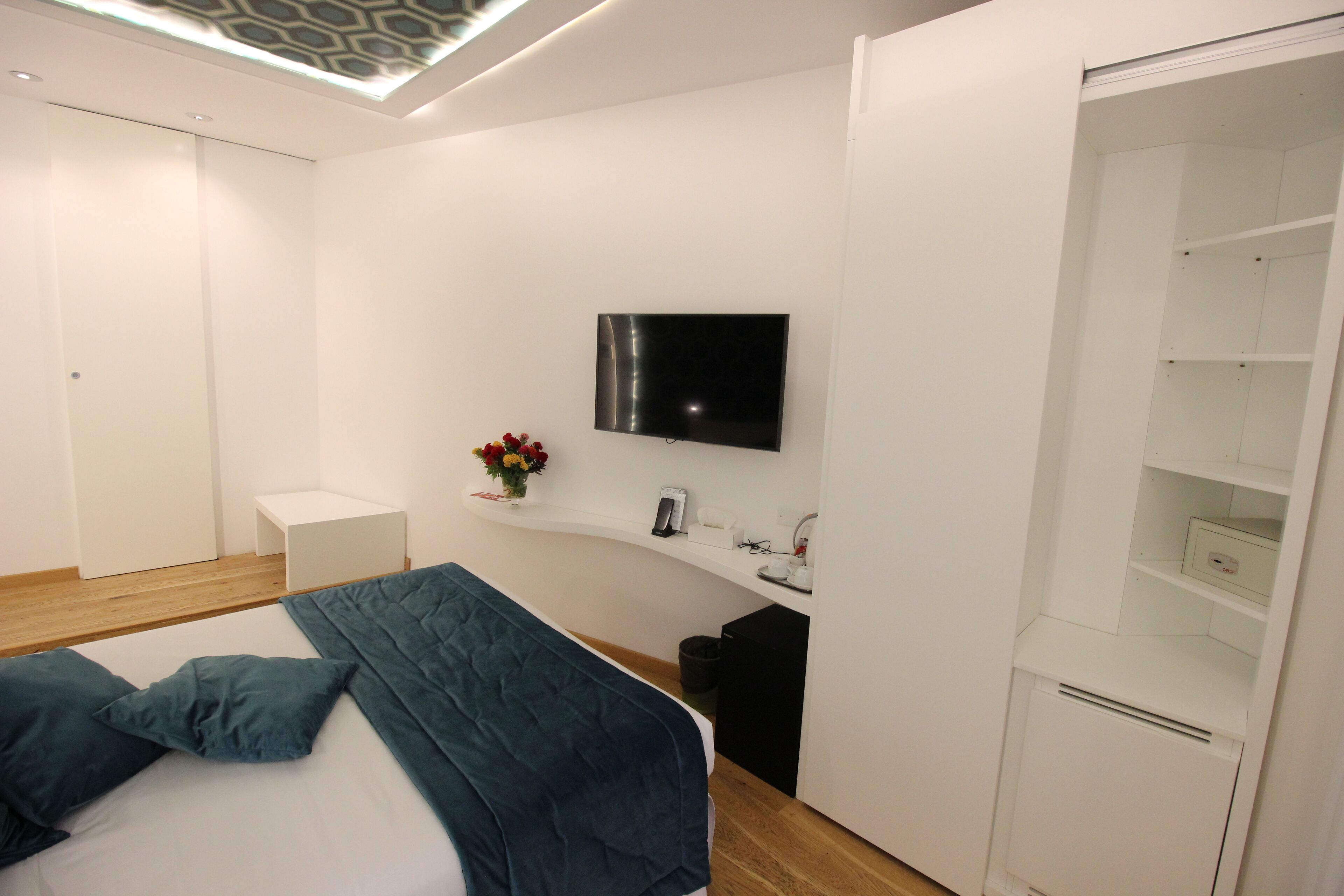Ein modernes Schlafzimmer mit Bett, Wand-Fernseher, Nachttisch und Kleiderschrank.
