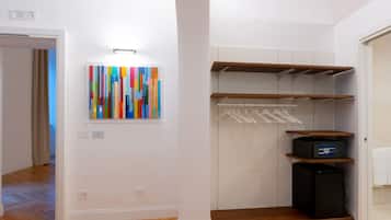 A walk-in closet with wooden shelves, a black appliance, and a colorful abstract painting on the wall.