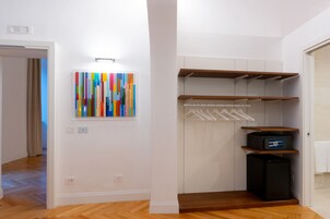 A walk-in closet with wooden shelves, a black appliance, and a colorful abstract painting on the wall.