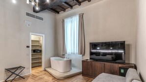 A modern living room with a built-in bathtub, a flat-screen TV, and a wooden cabinet.
