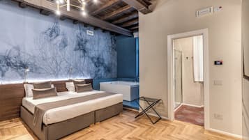 Un dormitorio con cama, mesita de noche, luz de pared, ventilador de techo y baño con bañera y ducha.