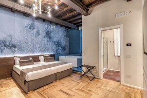 A bedroom with a bed, a nightstand, a wall-mounted light, a ceiling fan, and a bathroom with a bathtub and shower.