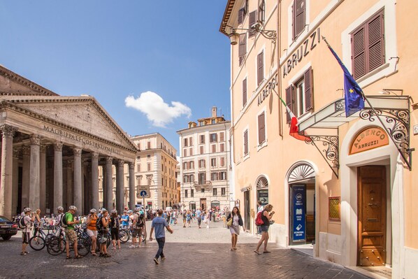 A cobblestone street with historic buildings, a crowd of people, and bicycles. - Hotel Abruzzi (Rome)