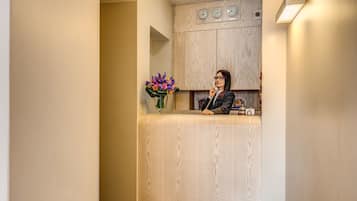 A reception area with a wooden reception desk, a vase of flowers, and a clock on the wall.