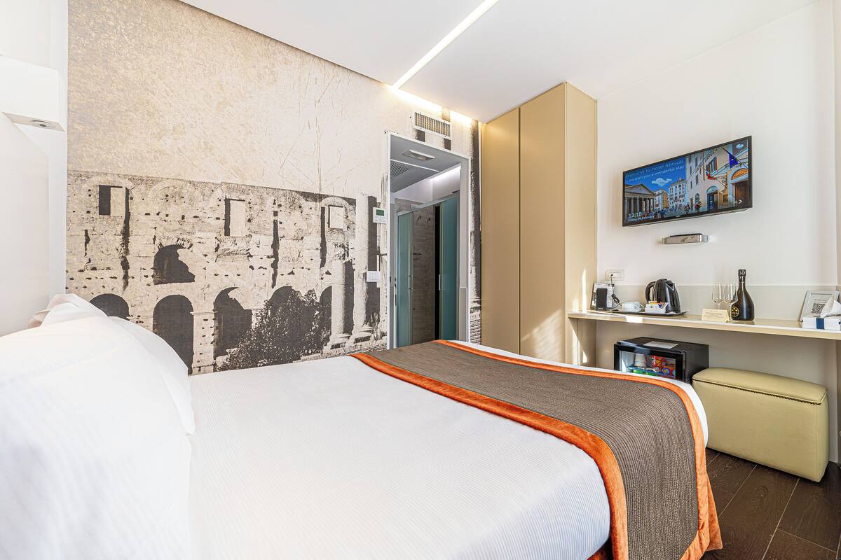 Una habitación de hotel con cama, escritorio, televisor y un cuadro en la pared.