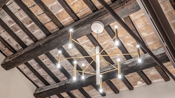 Un soffitto con travi in legno a vista e un lampadario moderno.