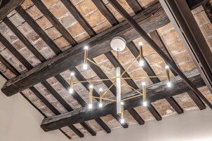 A ceiling with exposed wooden beams and a modern chandelier.