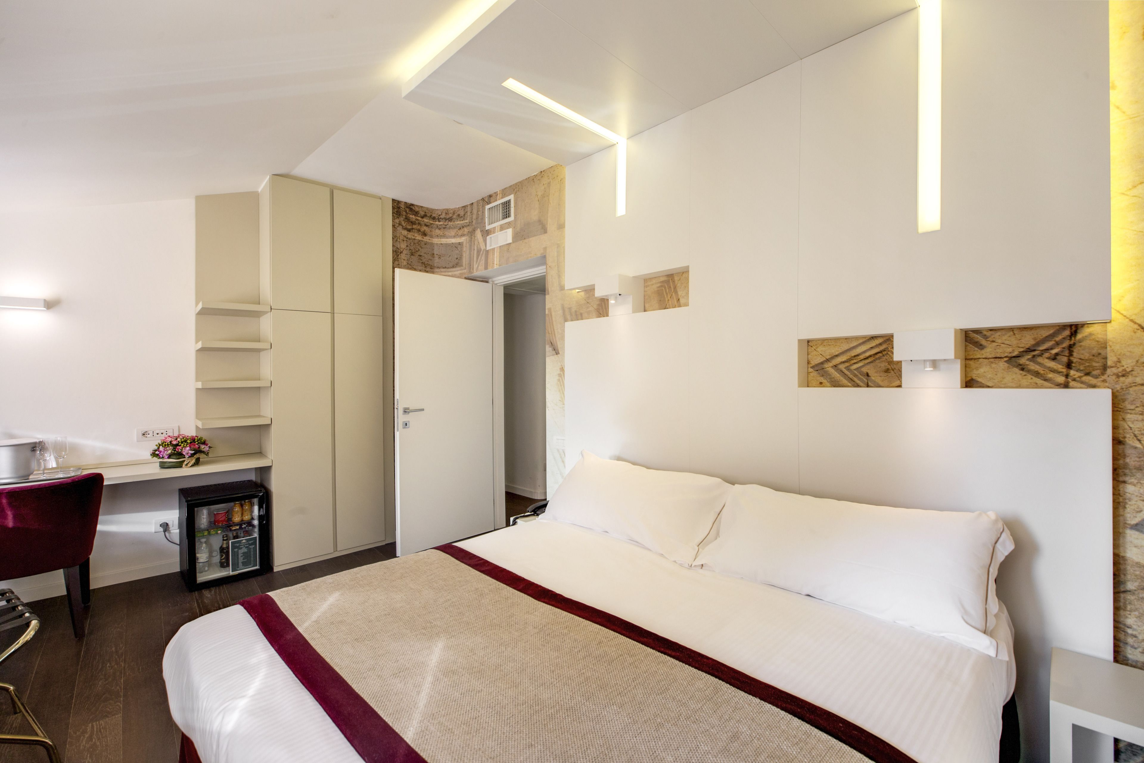 Una habitación de hotel moderna con una cama grande, un escritorio y un minibar.