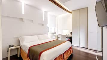 Quarto de hotel com uma cama grande, uma escrivaninha, uma cadeira e uma televisão.