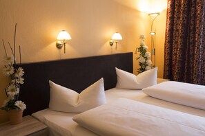 A hotel room with two beds, a nightstand, a potted plant, and wall-mounted lamps. - Hotel am Hermannplatz (Berlin)