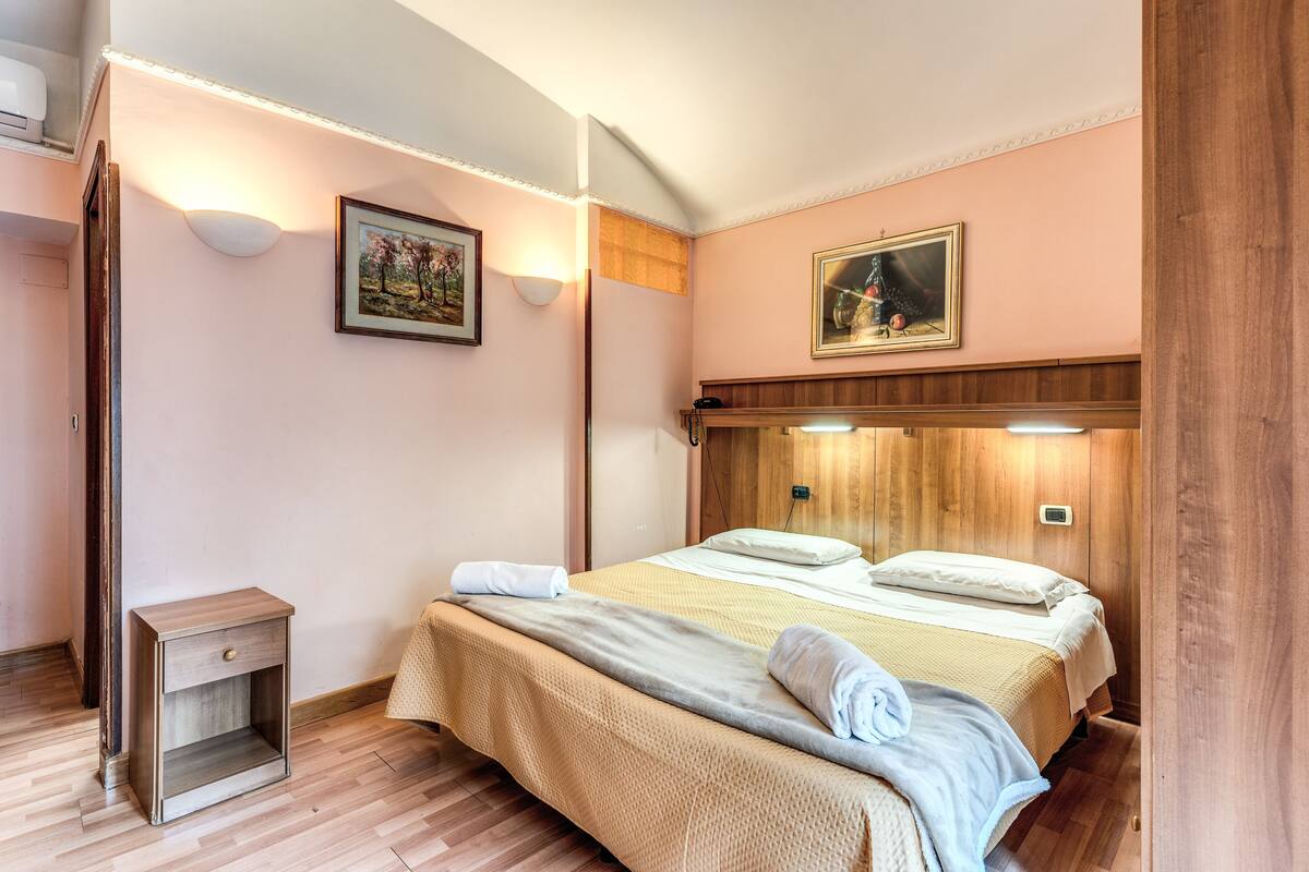 A neatly arranged bedroom with a bed, bedside table, and wall-mounted light fixtures.