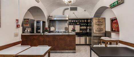 Restaurante com balcão central, cadeiras brancas e um lustre.
