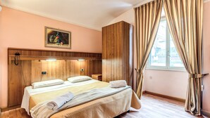 Quarto de hotel com cama grande, cabeceira de madeira, um quadro na parede e uma janela com cortinas.