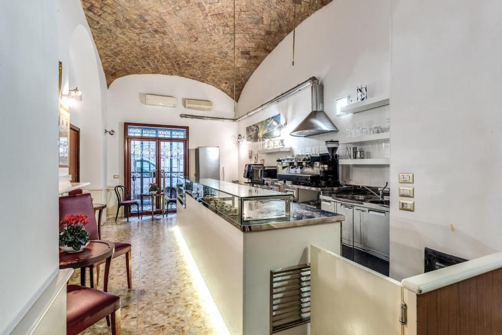 Una cucina con isola centrale, una zona pranzo con sedie e vista attraverso una porta vetrata.