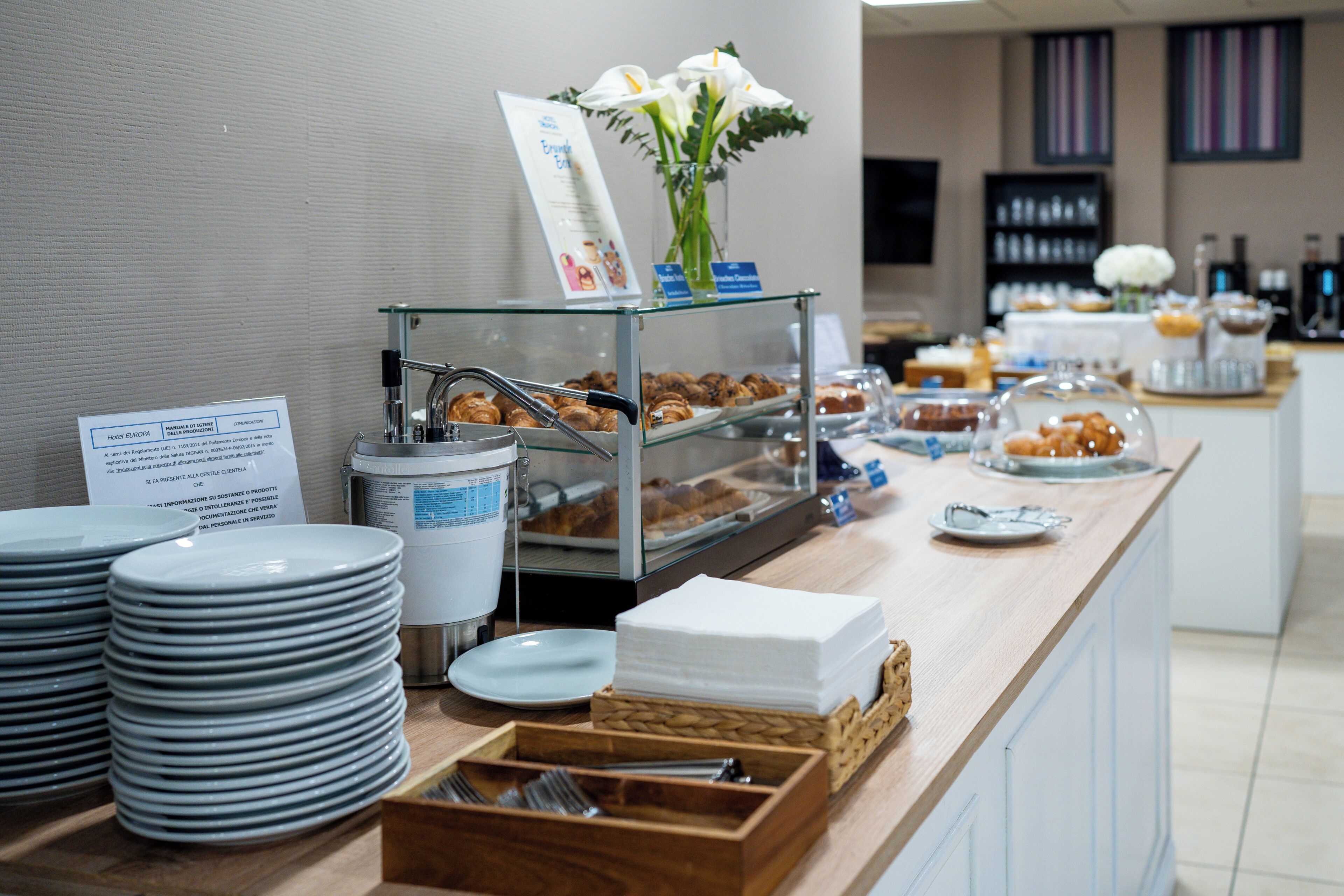A buffet setup with plates, bowls, and utensils.