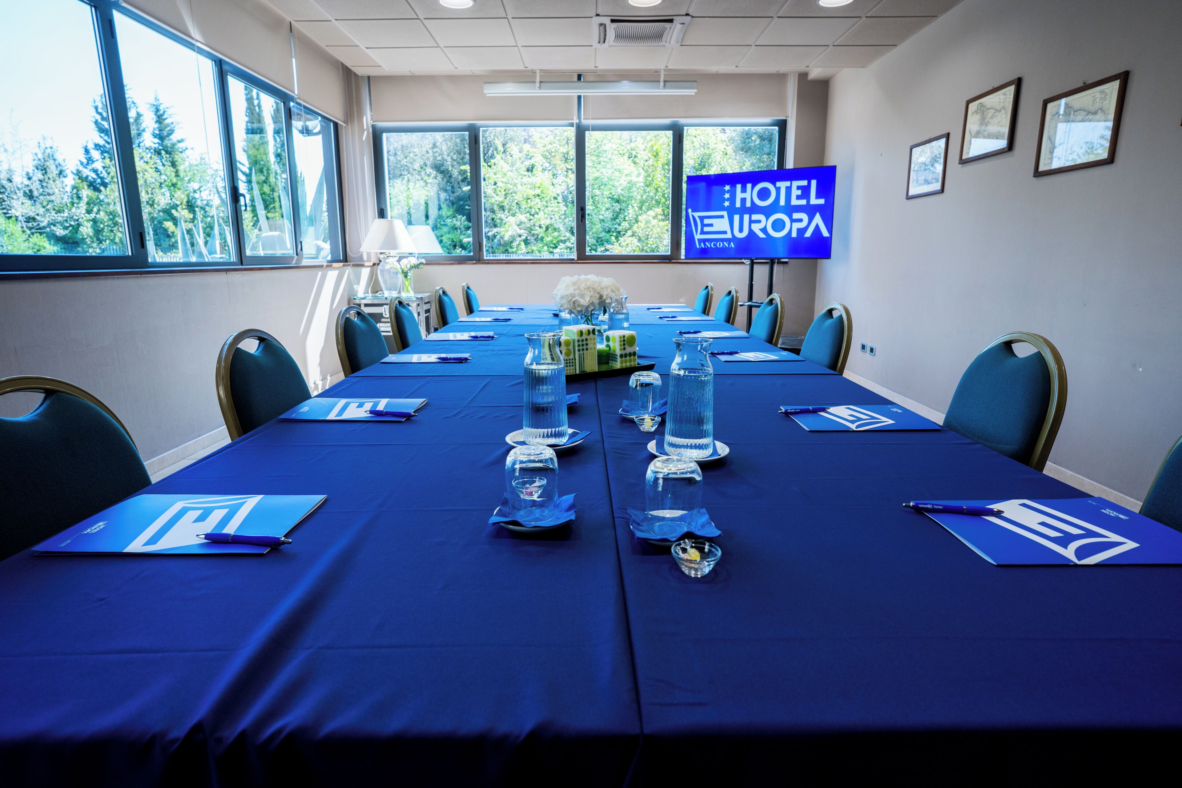 Una sala conferenze con un lungo tavolo, sedie e un cartello che indica che si tratta di un hotel.