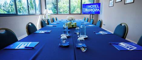 Una sala conferenze con un lungo tavolo, sedie e un cartello che indica che si tratta di un hotel.