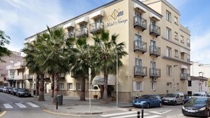 A multi-story hotel with balconies, palm trees, and parked cars. - Hotel Ninays (Lloret de Mar)