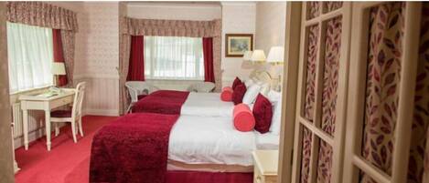 A hotel room with two beds, a desk, and a chair.
