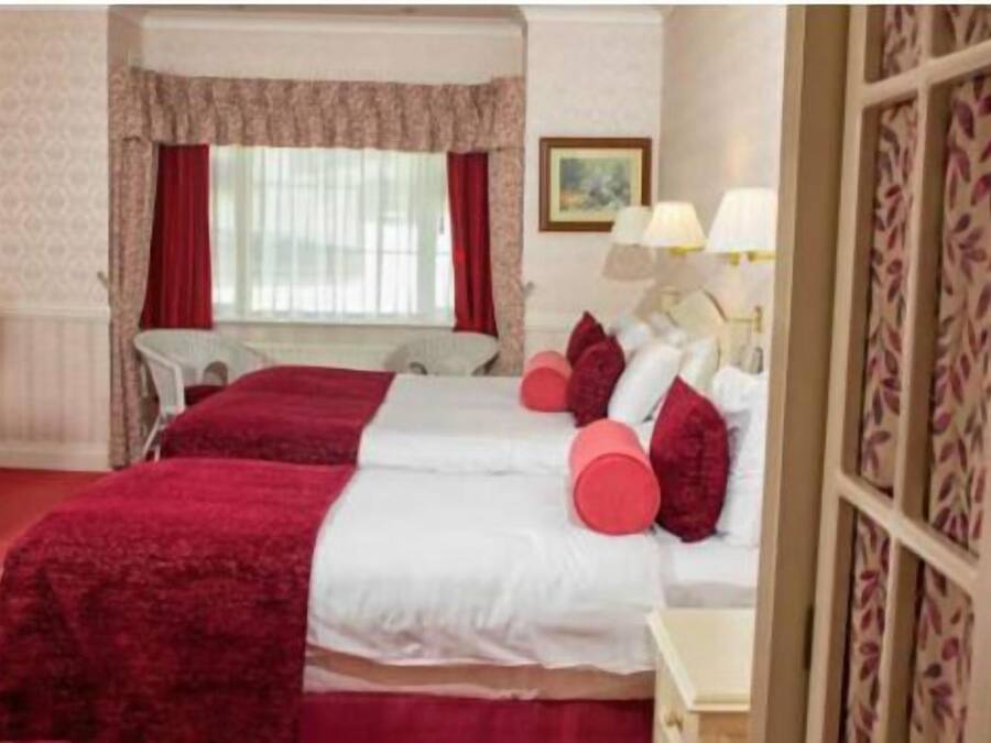 A hotel room with two beds, a desk, and a chair.